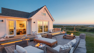 Luxury beachfront cottage with ocean-view deck, outdoor fire pit, and cozy patio seating at sunset